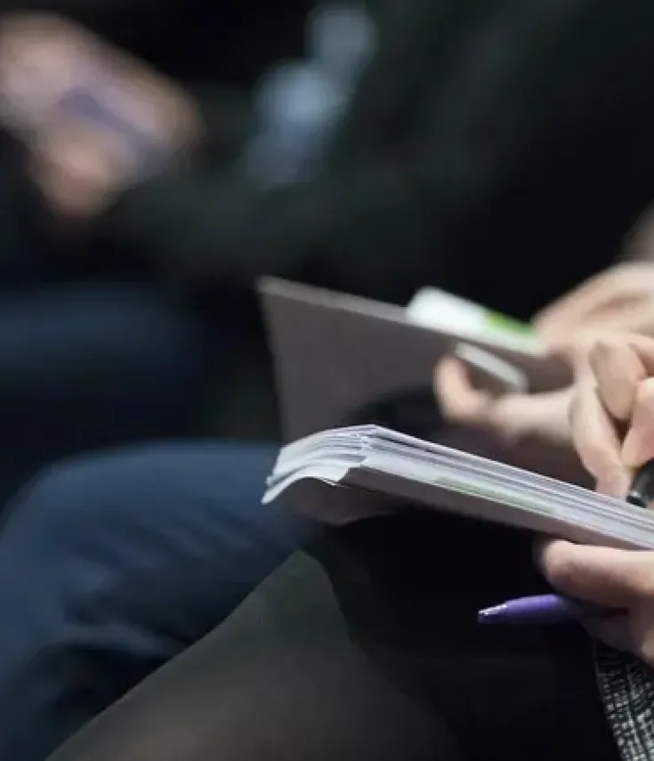 Estudiantes del Grado en Periodismo de la UCAM tomando notas durante una rueda de prensa para la redacción de noticias con impacto social. 